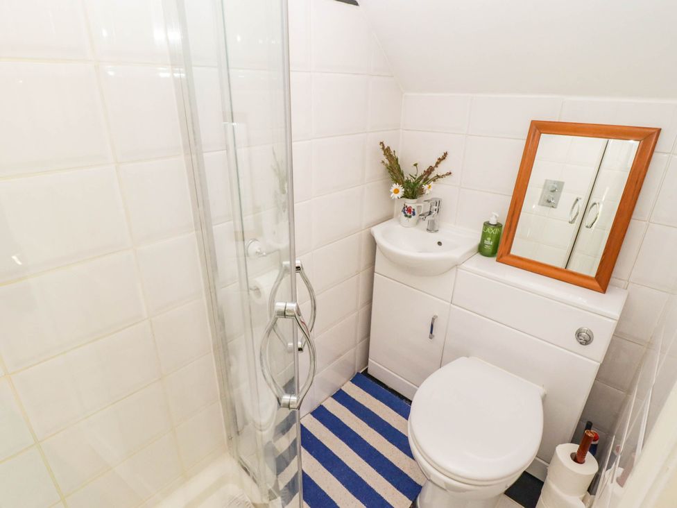 A bathroom with a shower, toilet, sink, and mirror at 11b Market Street in Narberth