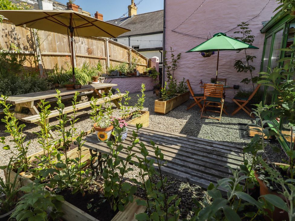A garden with wooden tables, chairs, and planters at 11b Market Street Narberth