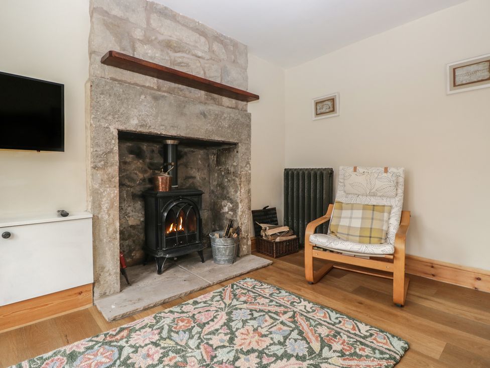 A living room with a fireplace and armchair at Bluebell Cottage in Heysham