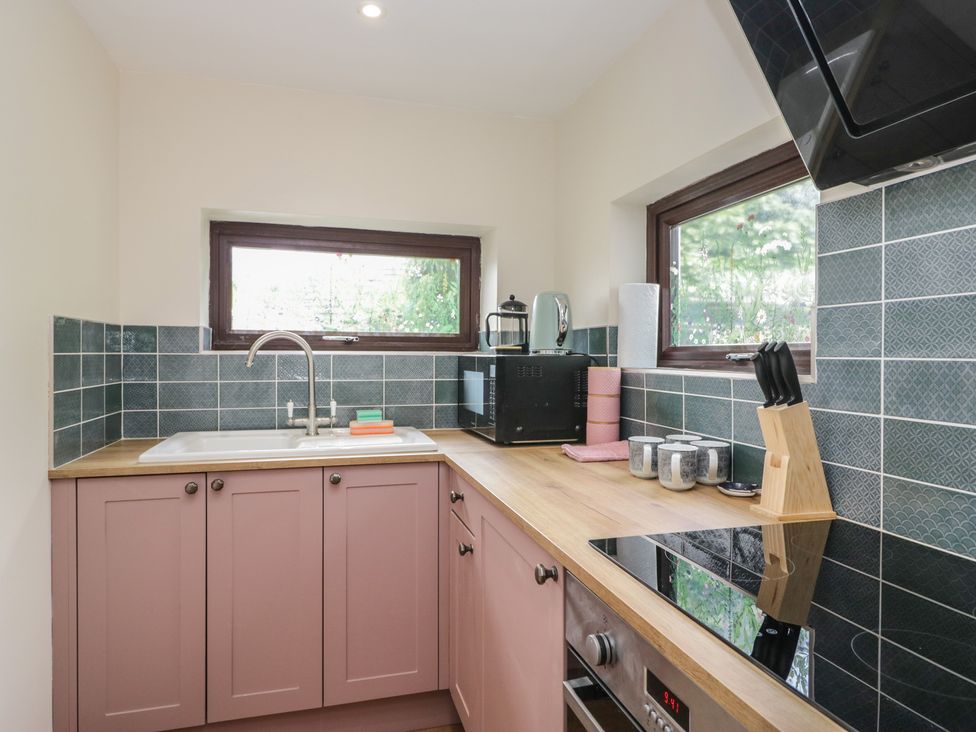 A kitchen with a sink, microwave, and counter at Bluebell Cottage in Heysham