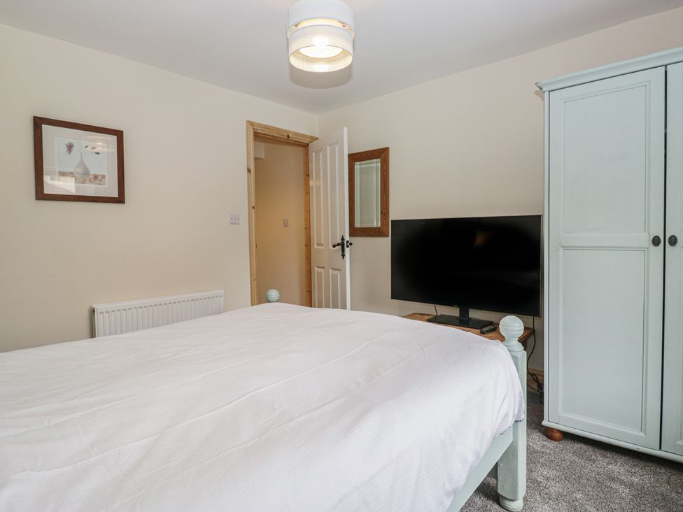 A bedroom with a bed and a television at Bluebell Cottage in Heysham
