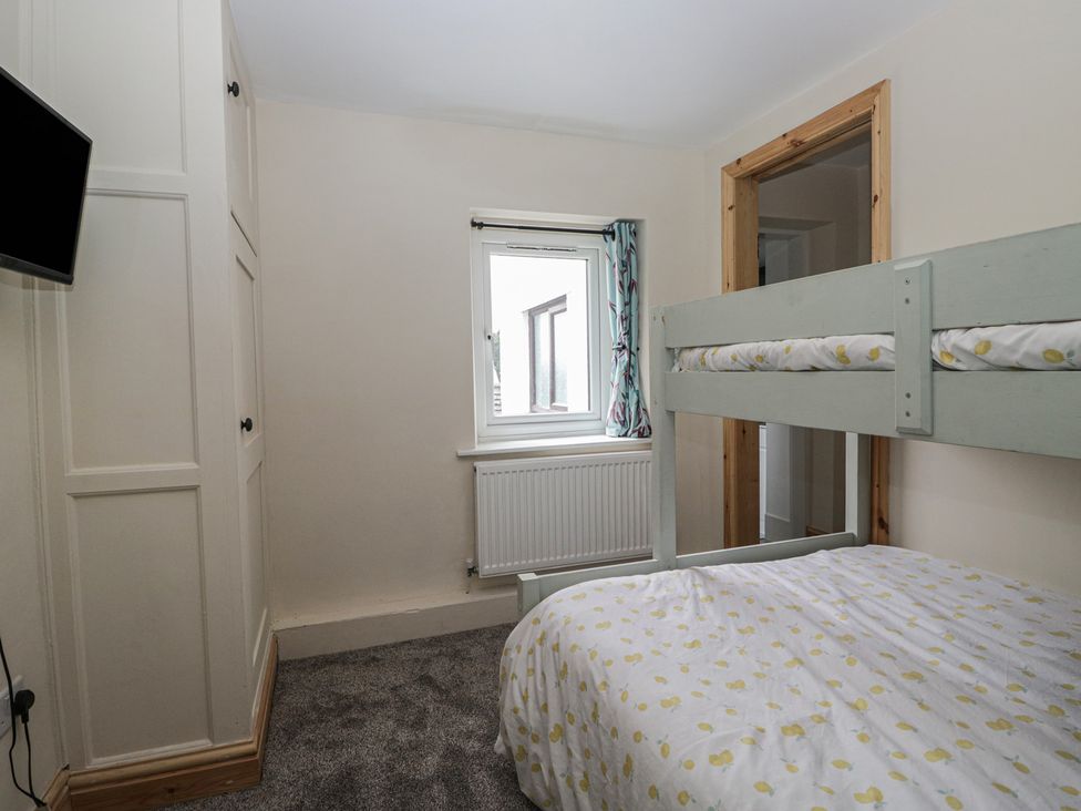A bedroom with a bunk bed and a television at Bluebell Cottage in Heysham