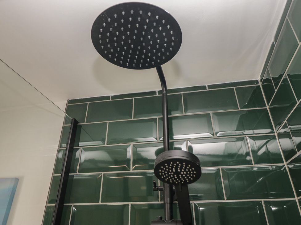 A shower head mounted on a wall in a bathroom at Bluebell Cottage in Heysham