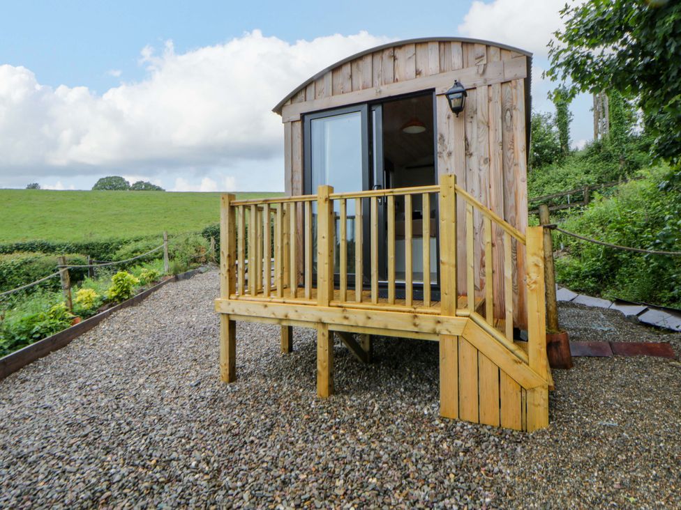 A wooden hut with steps on a gravel area at The Hut in Llandysul