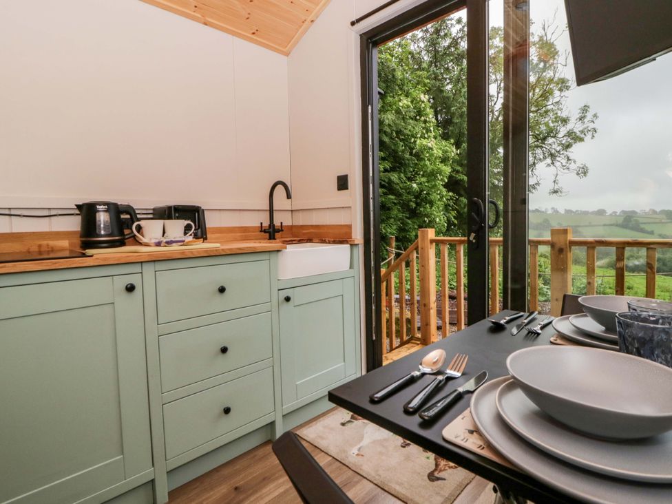 A kitchen with sink, cabinets, and dining table at The Hut in Llandysul