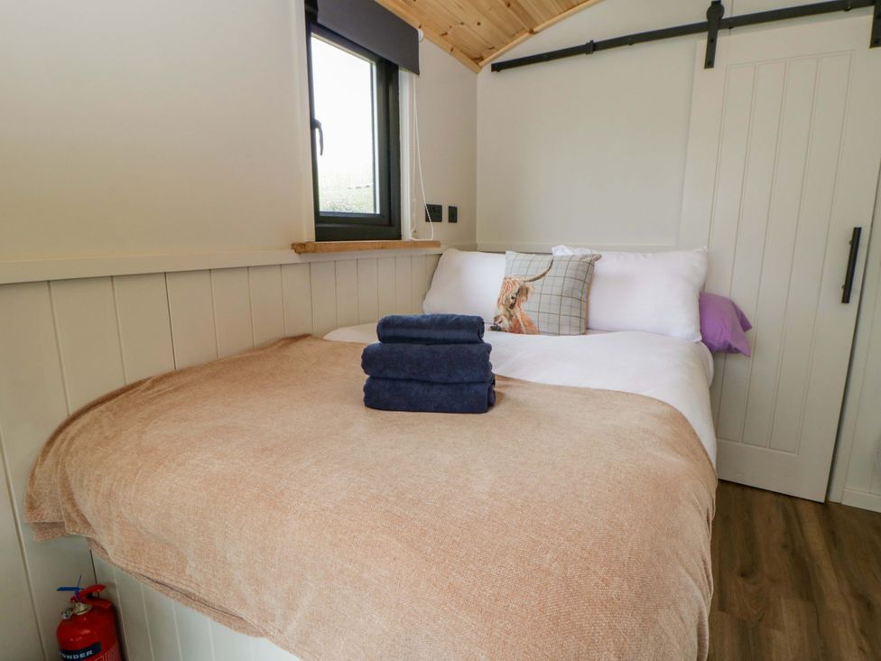 A bedroom with a bed and towels at The Hut in Llandysul
