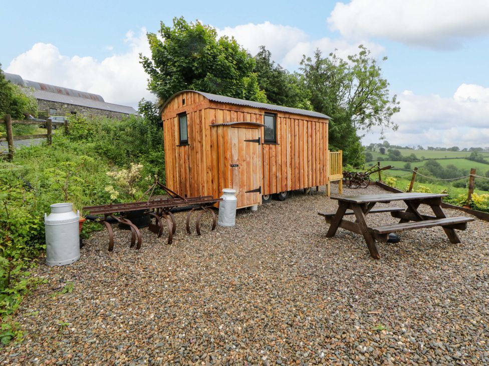 A wooden hut and picnic table in an outdoor area at The Hut in Llandysul