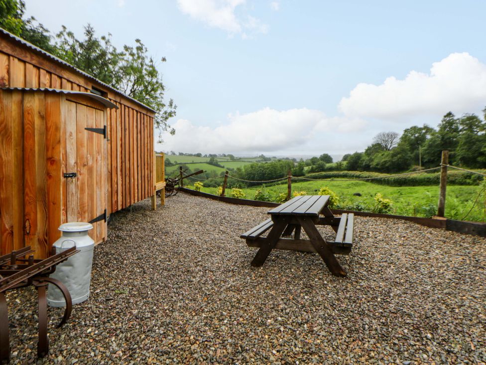 An outdoor area with a wooden cabin and picnic table at The Hut in Llandysul