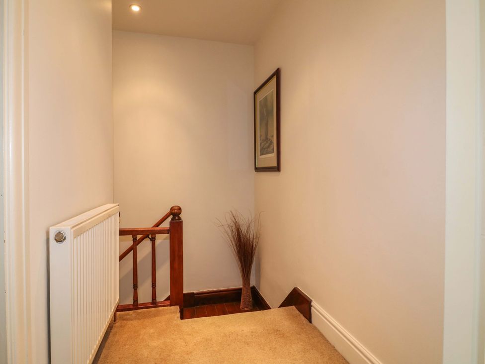 A hallway with a staircase and radiator at The Chimes in Hope Valley