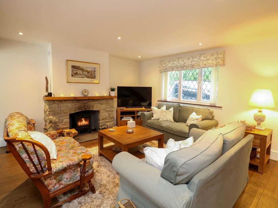 A living room with a sofa, armchair, coffee table, and fireplace at The Chimes in Castleton, Peak District