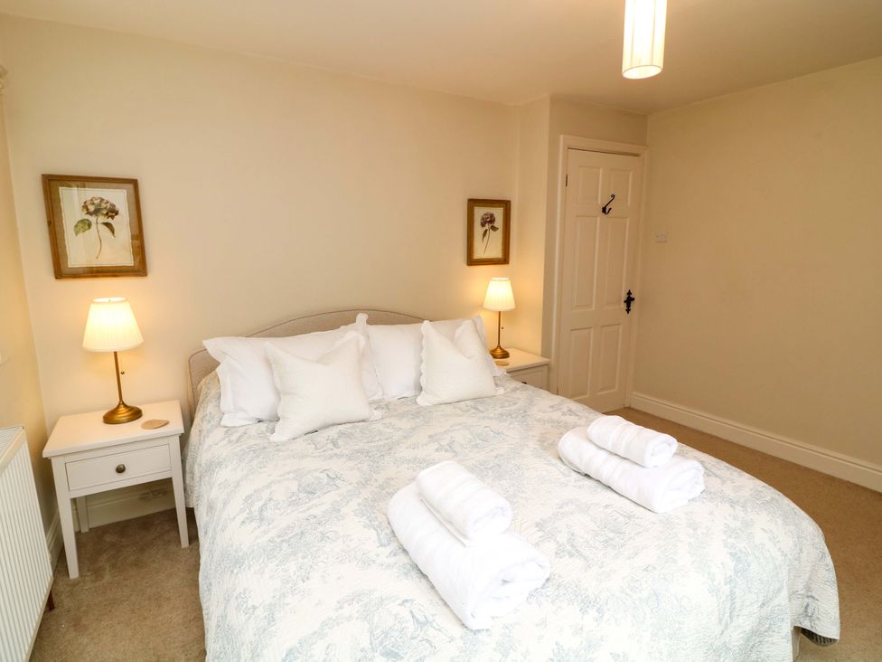 A bedroom with a bed, bedside table, and lamps at The Chimes in Castleton, Peak District