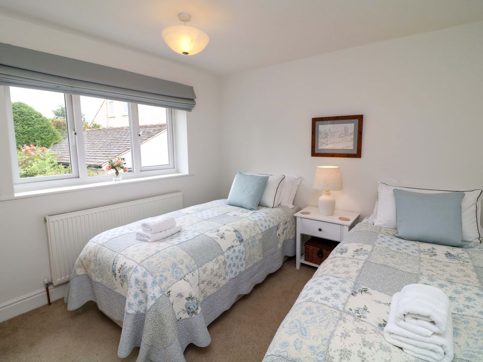 A bedroom with two beds and a side table at The Chimes in Castleton, Peak District