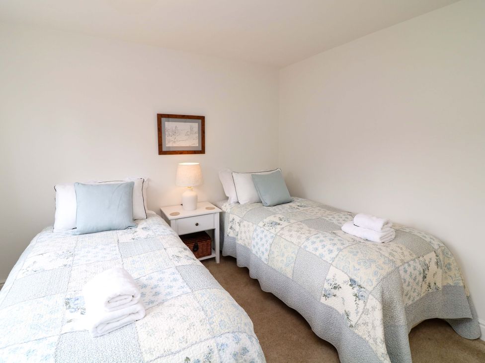 A bedroom with two single beds and a nightstand at The Chimes in Castleton, Peak District