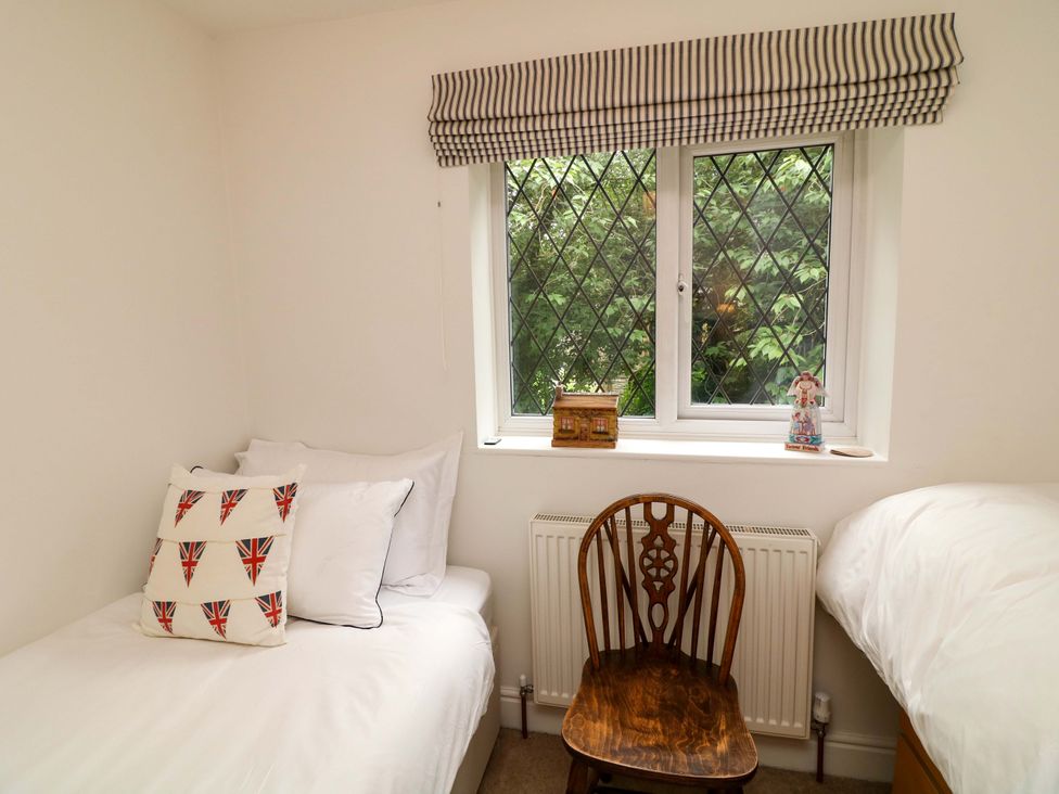 A bedroom with a window, chair, and two beds at The Chimes in Castleton, Peak District