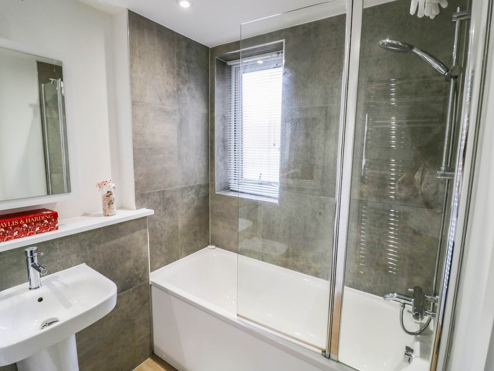 A bathroom with a bathtub, shower, and sink at 4 Goldcrest Close in Daventry