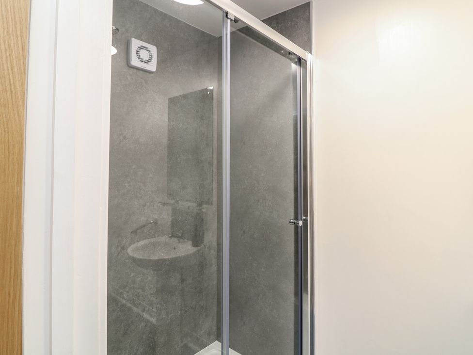 A shower area with a glass door and gray wall tiles at Catley, Billinghay, Lincolnshire