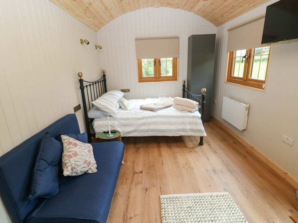 A bedroom with a bed and sofa at Shepherd Hut 2