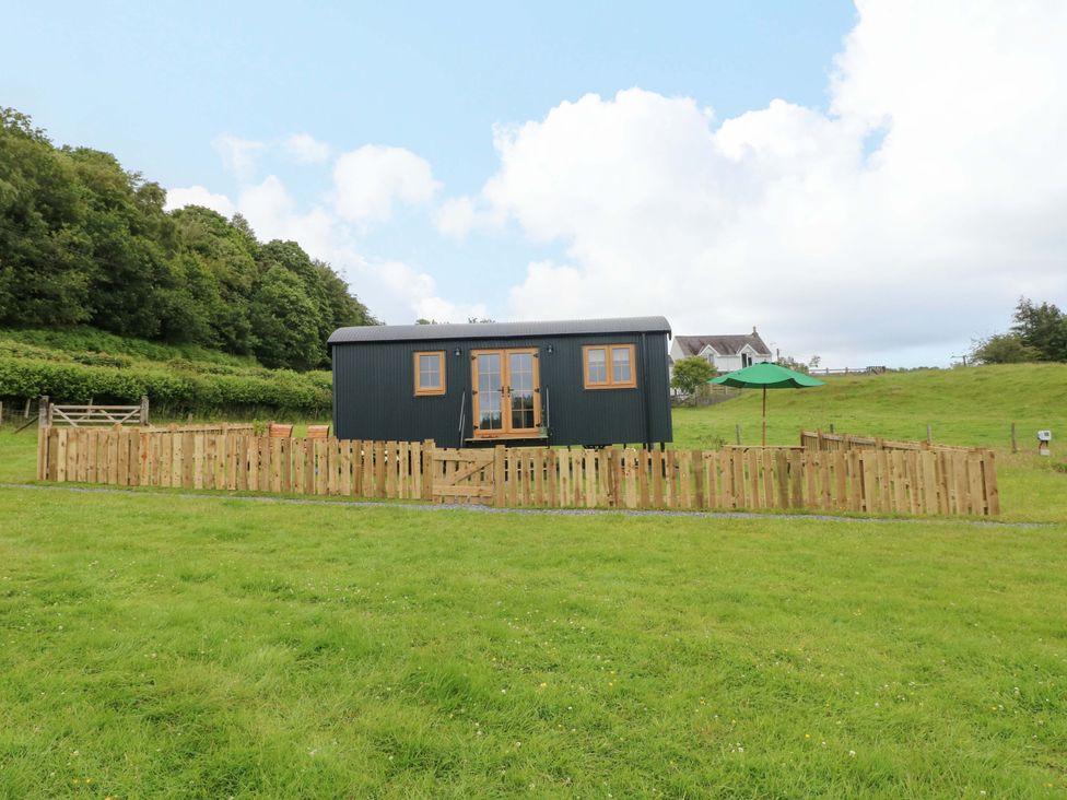 A hut with a fence and an umbrella at Shepherd Hut 2 in 