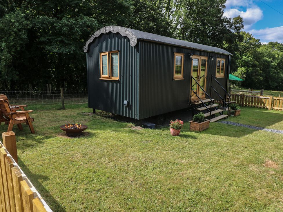 A shepherd's hut with a fire pit and seating area at Cwtch Y Bugail 2 Near Llandeilo