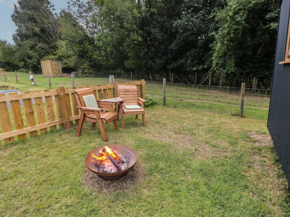 A garden with a fire pit and wooden chairs at Cwtch Y Bugail 2 Near Llandeilo