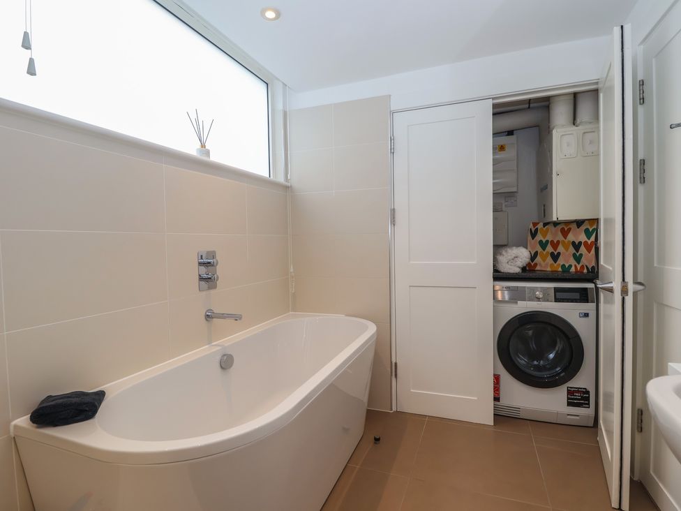 A bathroom with a bath tub and washing machine at 5 Sails Dartmouth