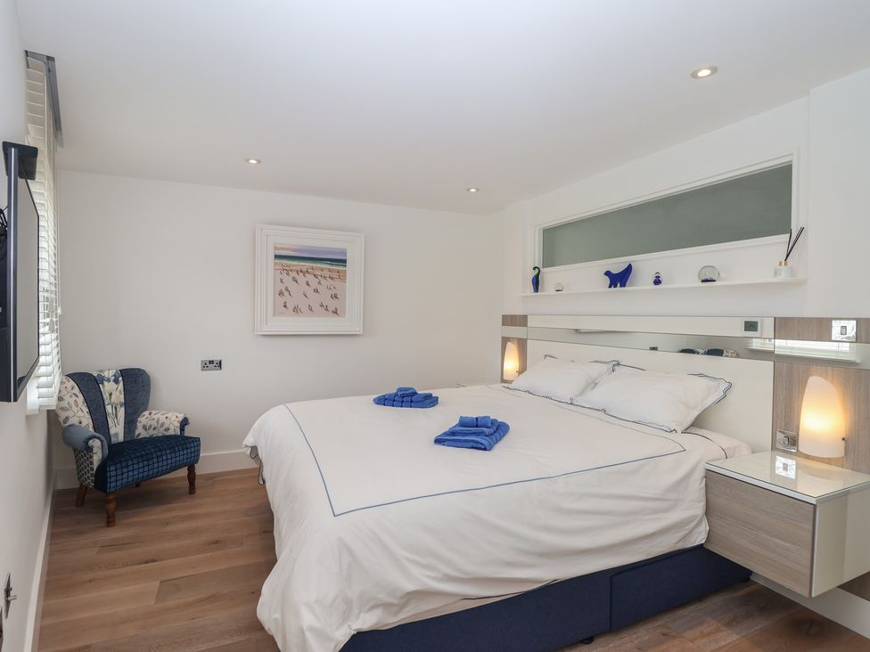 A bedroom with a bed, bedside tables, and a chair at 5 Sails in Dartmouth