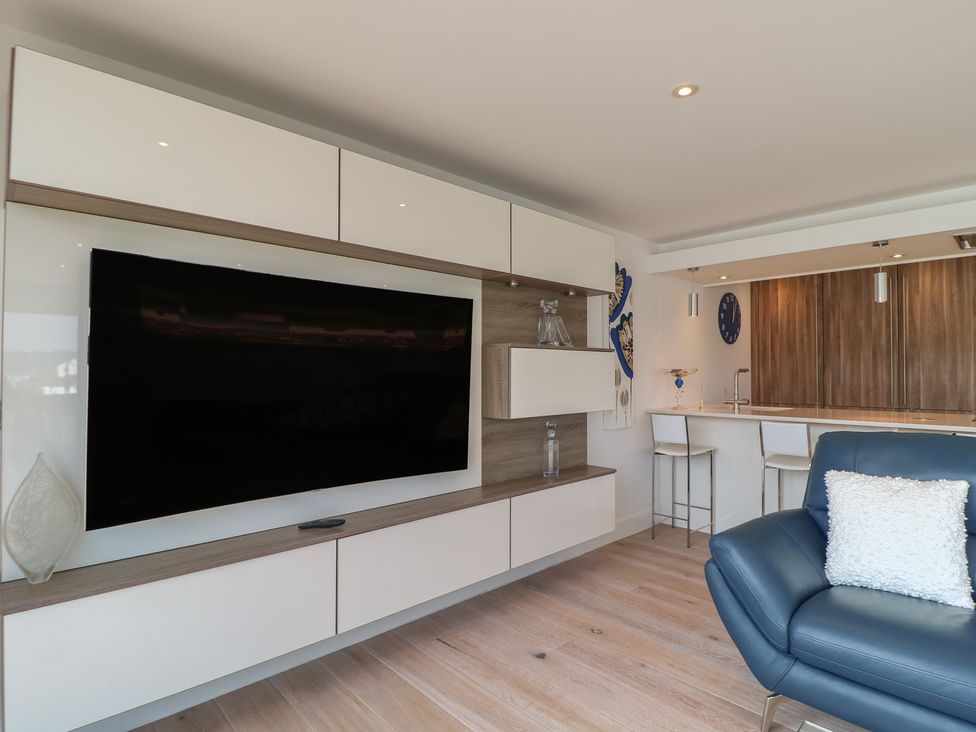 A living room with a television and bar stools at 5 Sails in Dartmouth