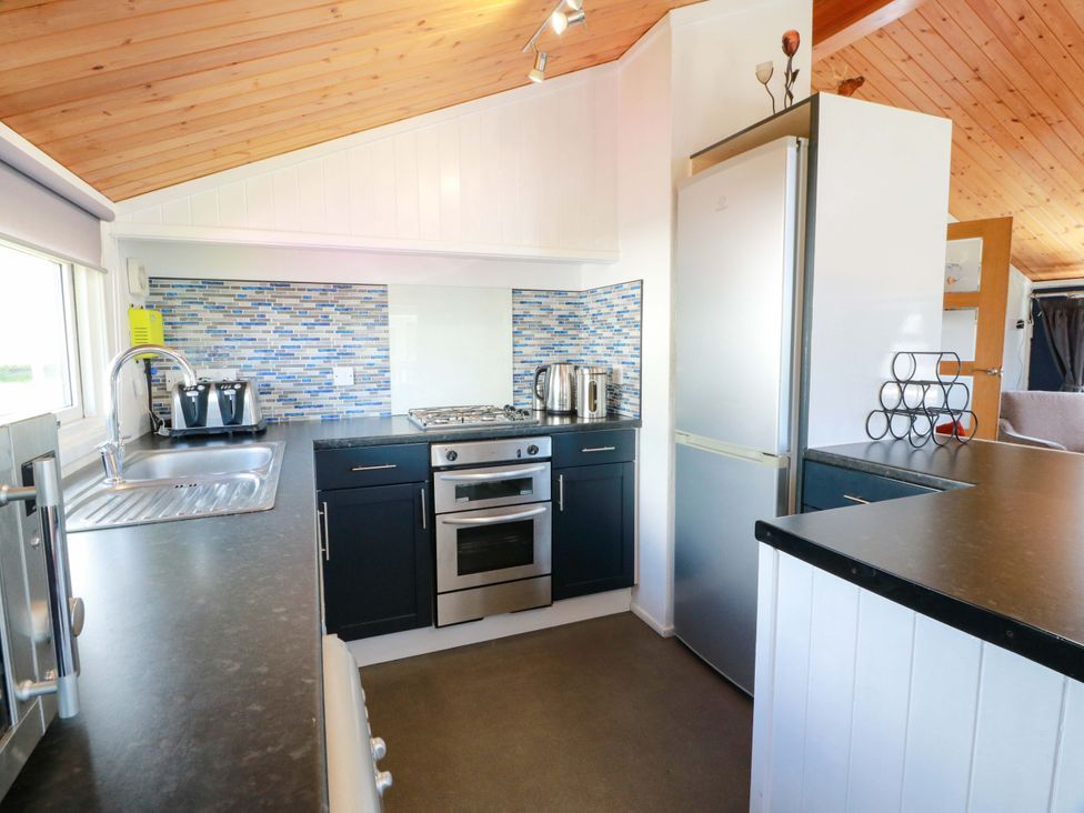 A kitchen with a countertop, sink, stove, and refrigerator at Queensway QW1 Dumfries