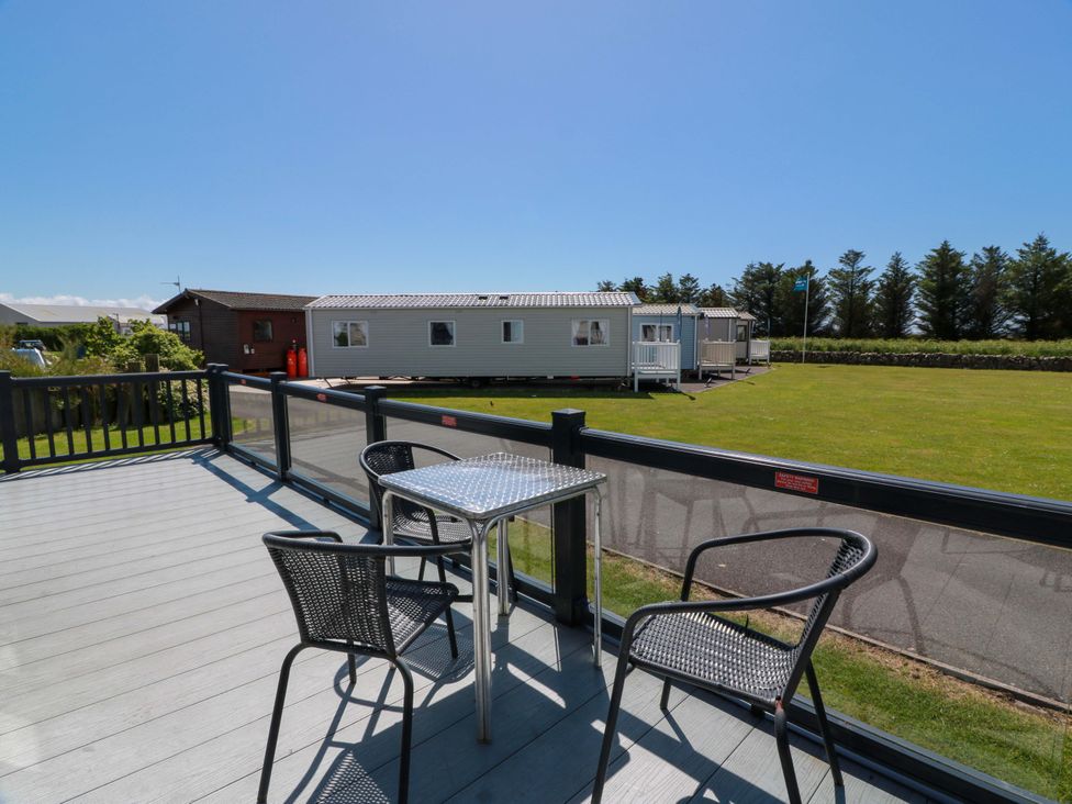 A deck with a table and chairs overlooking caravans at Queensway QW1 Dumfries