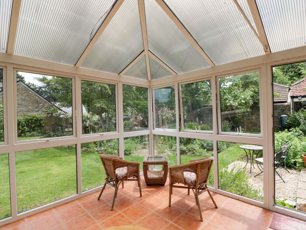 A conservatory with wicker chairs and a table at The Garden Studio Bremhill near Calne