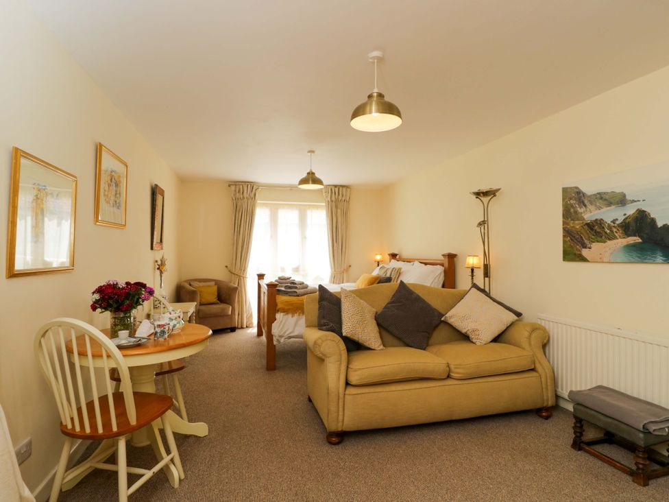 A living room with a sofa, coffee table, and dining area at The Garden Studio in Bremhill near Calne