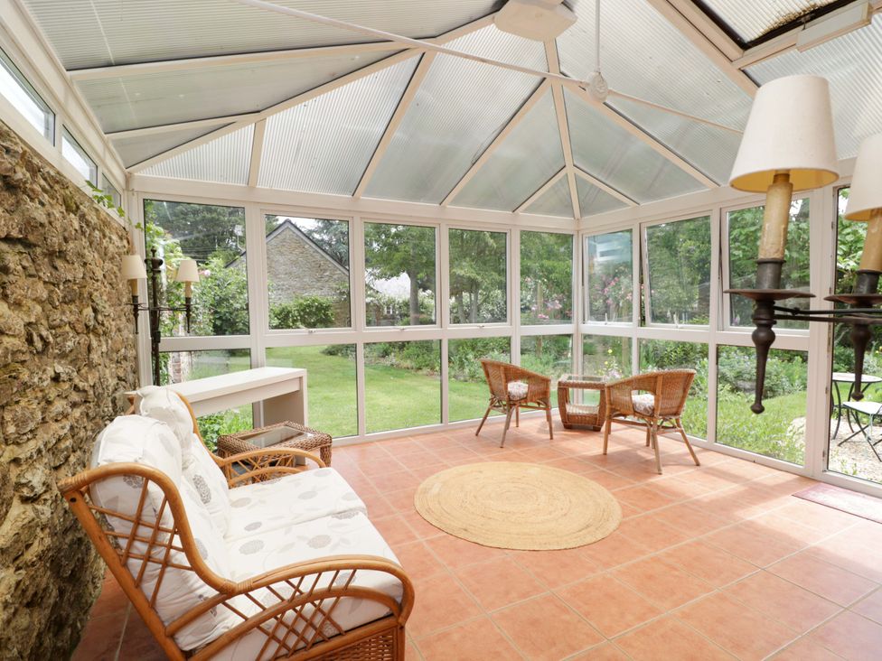 A conservatory with seating and a view of the garden at The Garden Studio in Bremhill near Calne