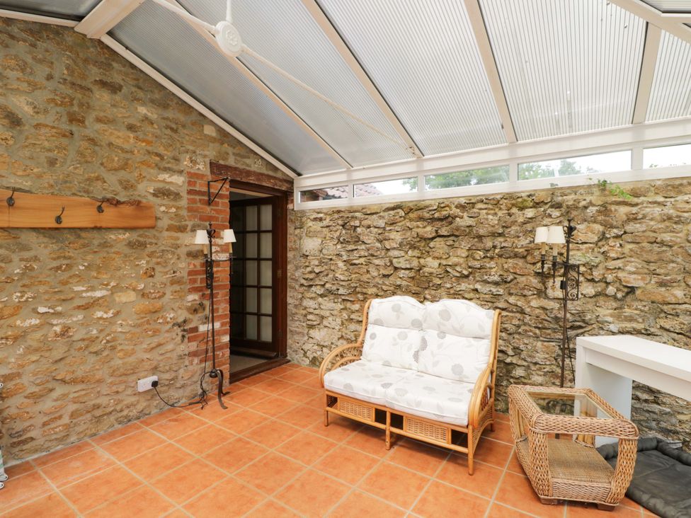 A conservatory with a sofa and table at The Garden Studio in Bremhill near Calne