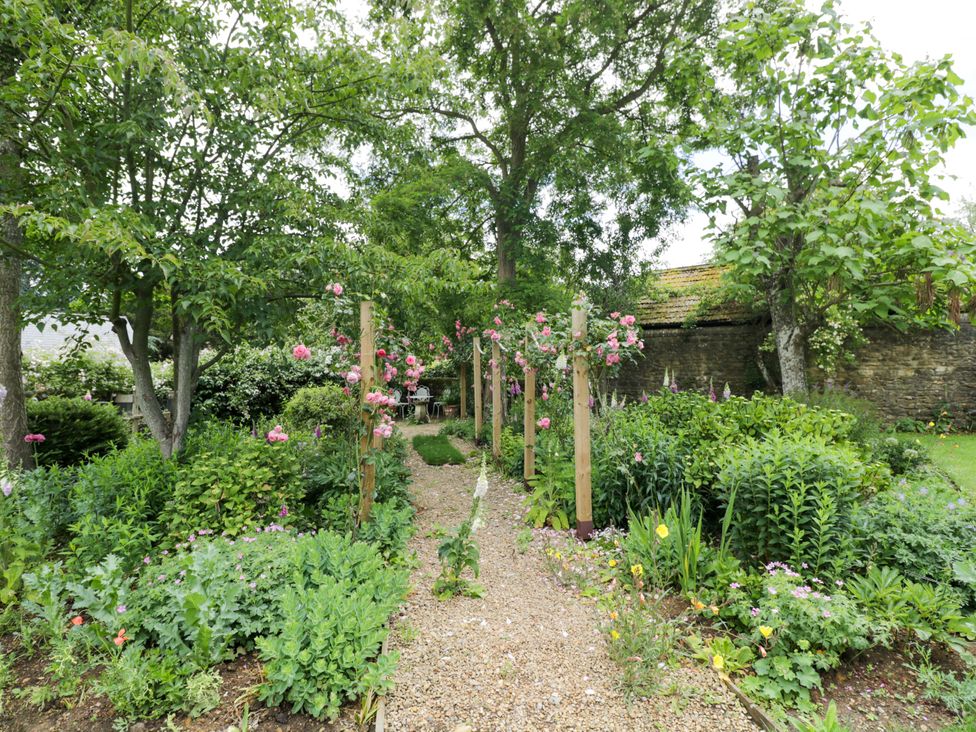 A garden with a pathway lined by flowers and trees at The Garden Studio in Bremhill near Calne