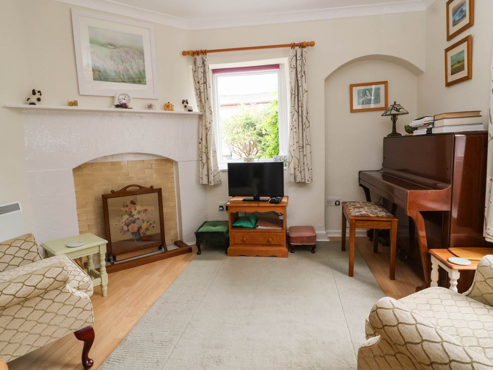 A living room with a piano and television at 96 Chapel Lane Butleigh