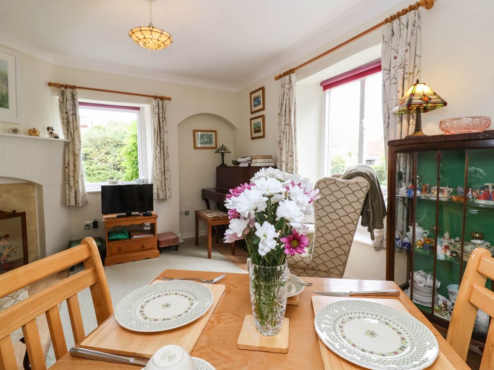 A dining room with a table, chairs, and flowers at 96 Chapel Lane in Butleigh