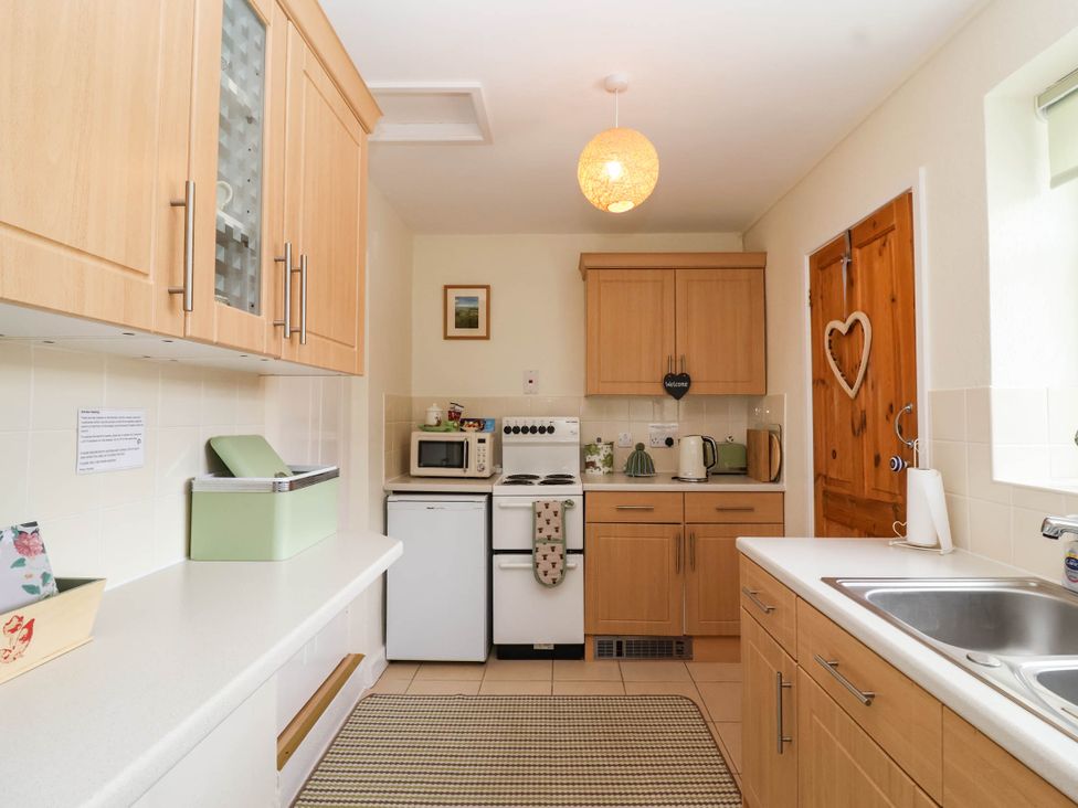 A kitchen with wooden cabinets and appliances at 96 Chapel Lane Butleigh