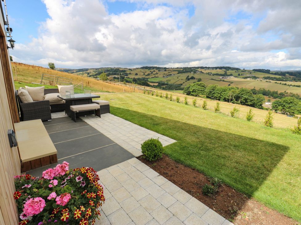 A garden with a patio and seating area at The Stables in Stainland