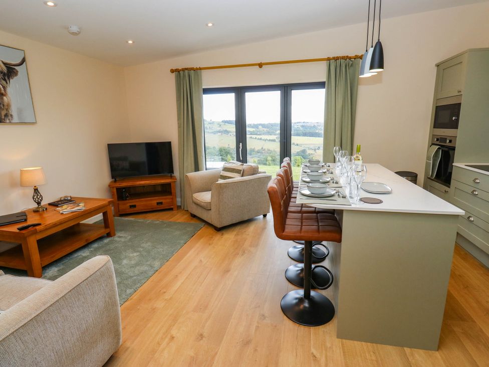 A living room with a sofa, television, and bar area at The Stables in Stainland