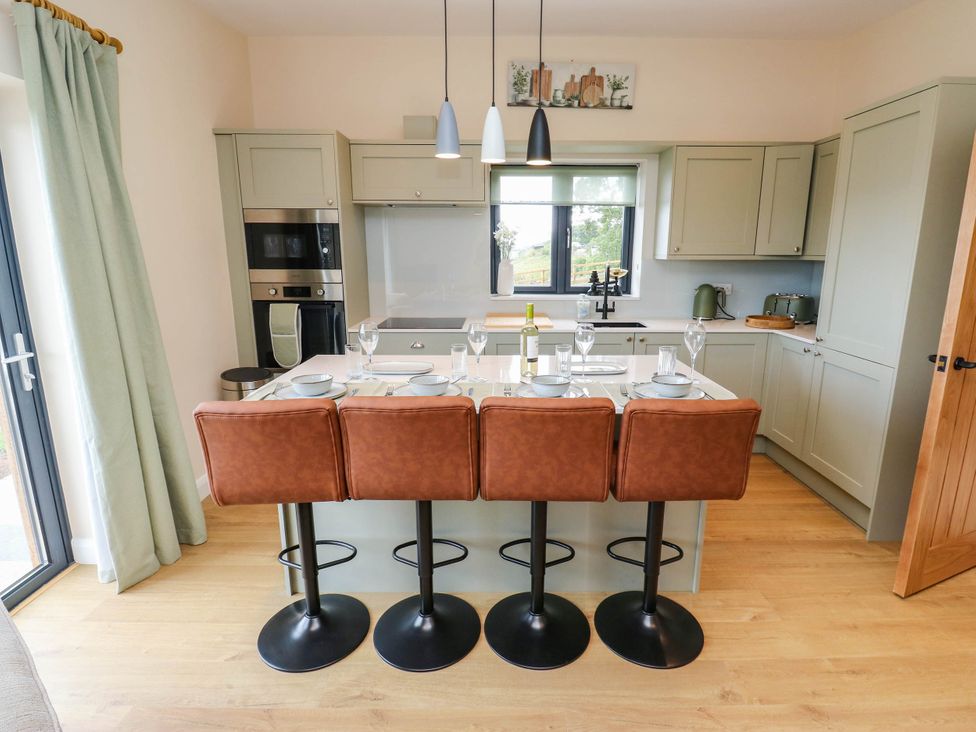 A kitchen with bar stools and kitchen appliances at The Stables in Stainland