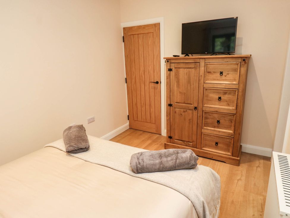 A bedroom with a bed and dresser at The Stables in Stainland