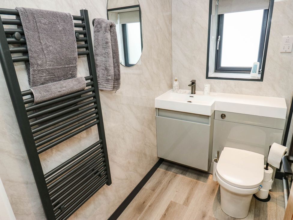 A bathroom with a towel radiator, sink, and toilet at The Stables in Stainland