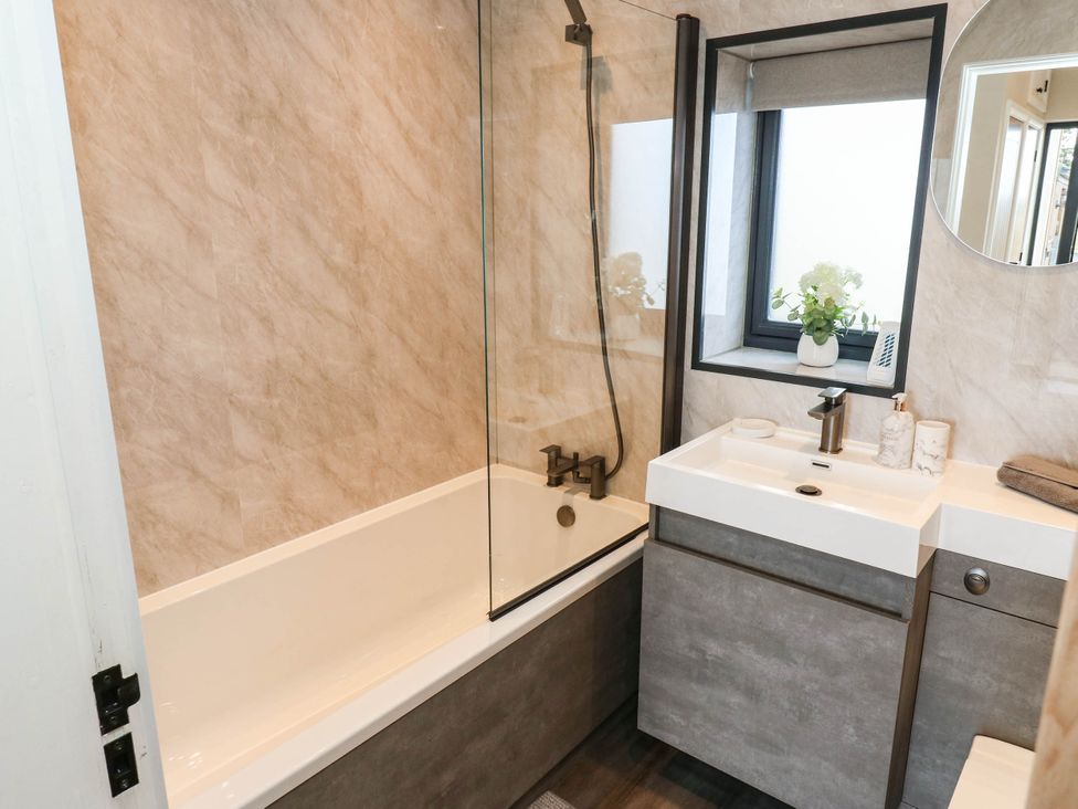 A bathroom with a bathtub, sink, and mirror at The Stables in Stainland