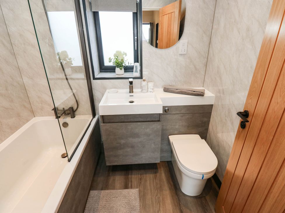 A bathroom with a bathtub, shower, toilet and sink at The Stables in Stainland