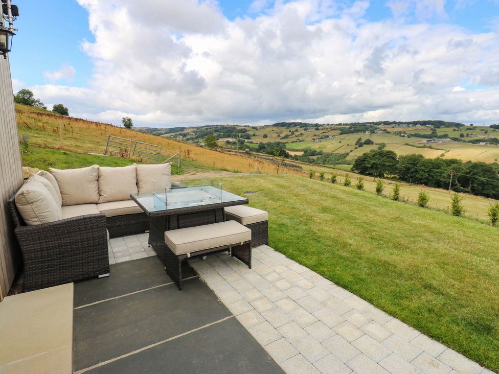 An outdoor area with a sofa and table overlooking hills at The Stables in Stainland