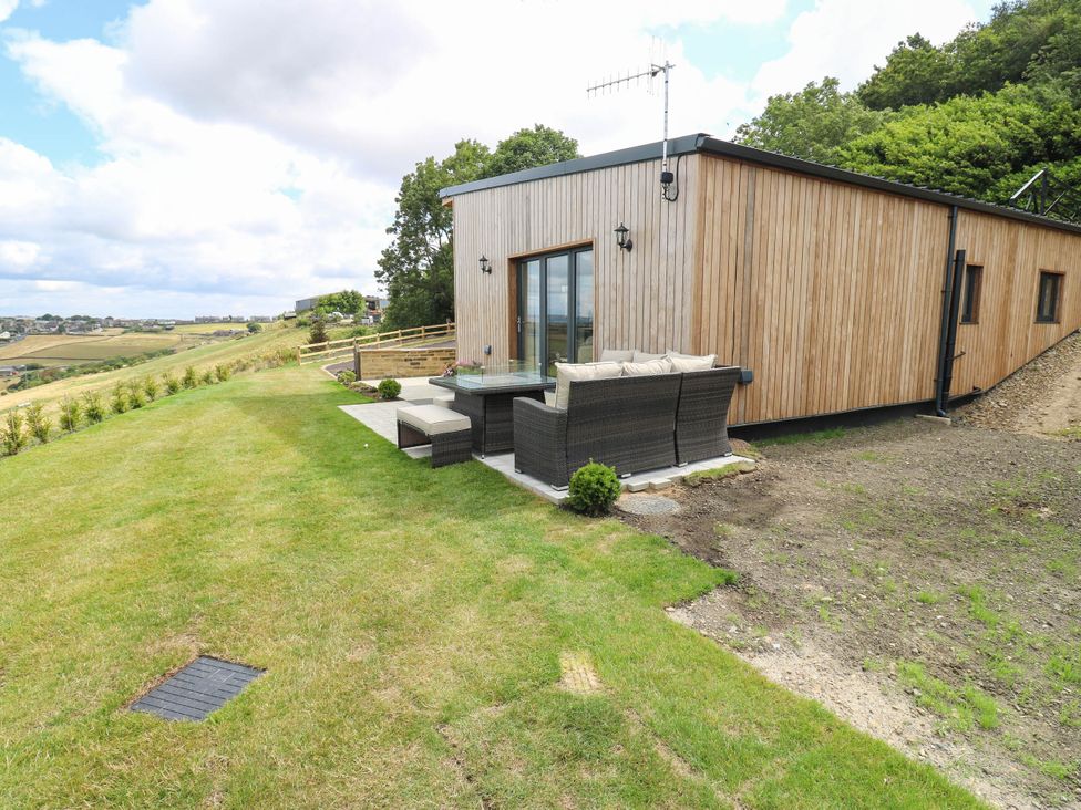 A garden with a house and outdoor furniture at The Stables in Stainland