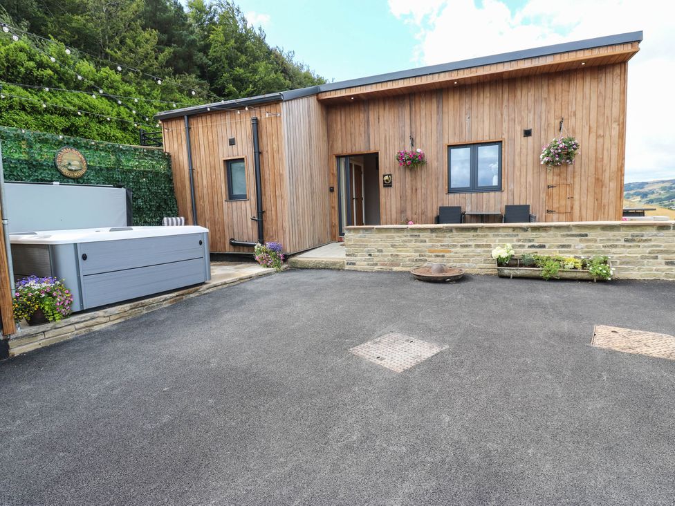 An outdoor area with a wooden building and hot tub at The Stables in Stainland