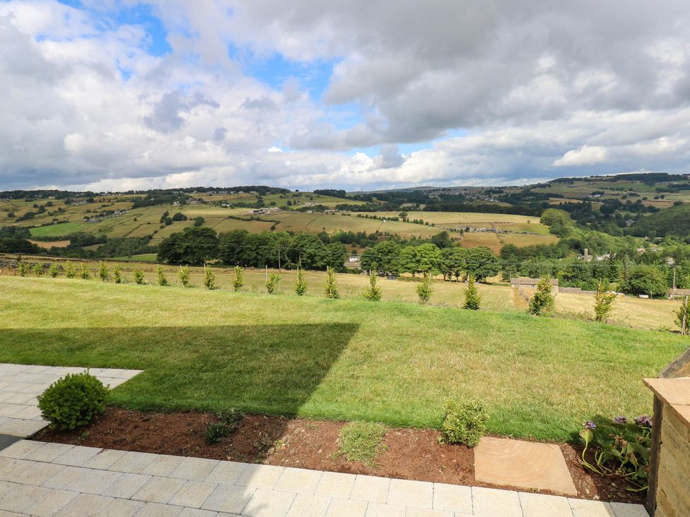 A garden view with grass and plants overlooking hills at The Stables in Stainland