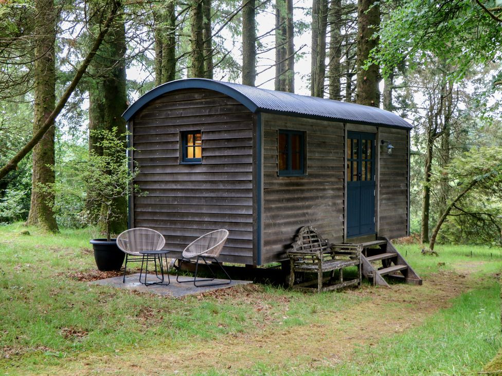 A view of a shepherds hut with chairs and a planter at Ridden Brake shepherds hut in Yelverton