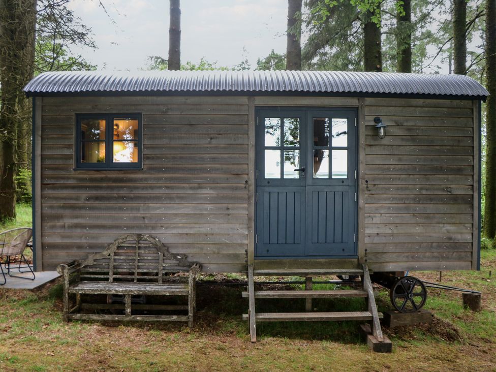 A shepherds hut with a wooden bench and steps at Ridden Brake shepherds hut Yelverton